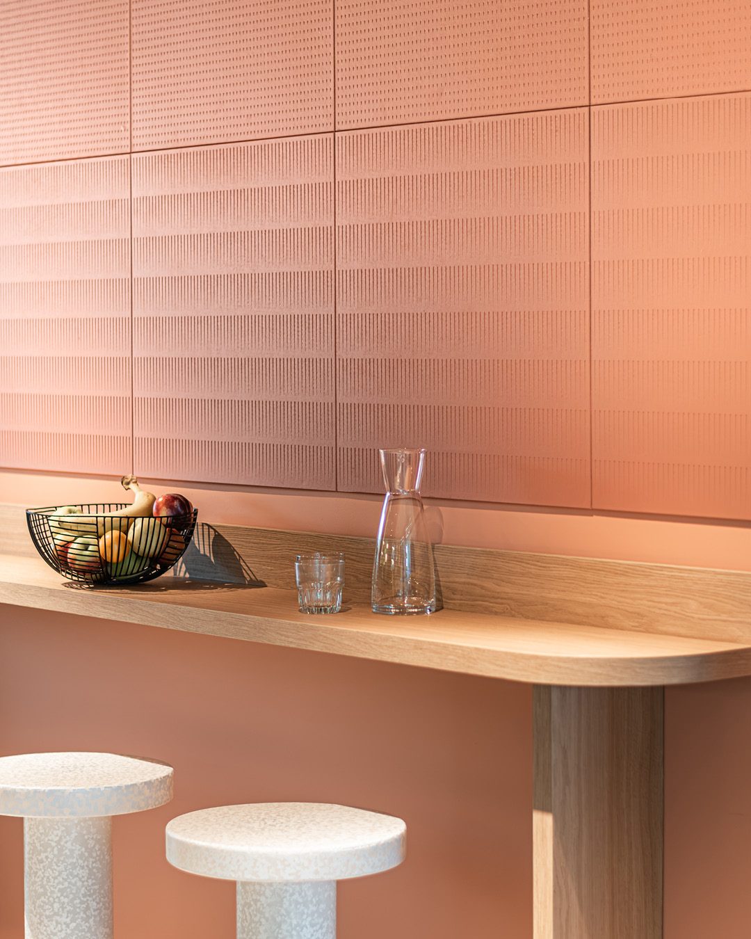 Terracotta Paper Waste Panels made from recycled paper waste as wall cladding above an oak bar counter with stools